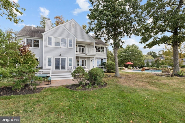 back of house with a balcony, a lawn, and a patio area