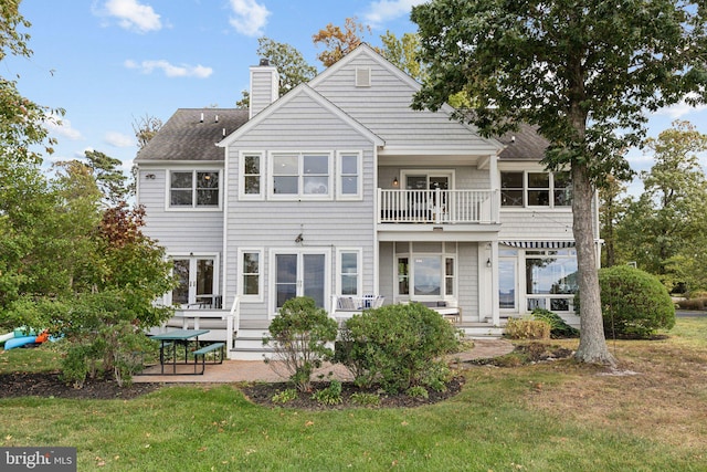 rear view of property featuring a yard, a balcony, and a patio area