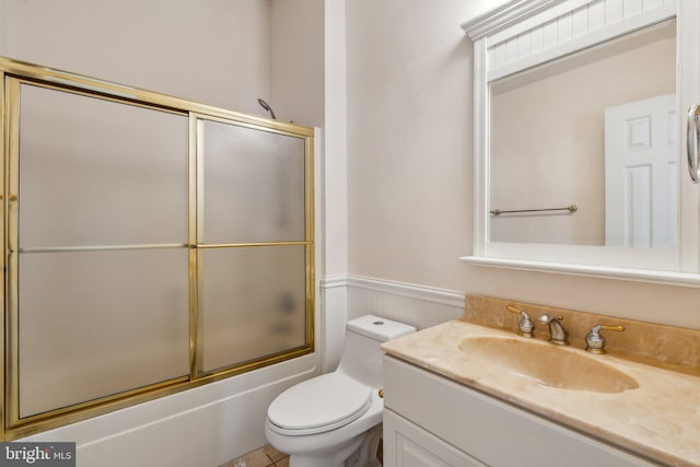 full bathroom with enclosed tub / shower combo, vanity, and toilet