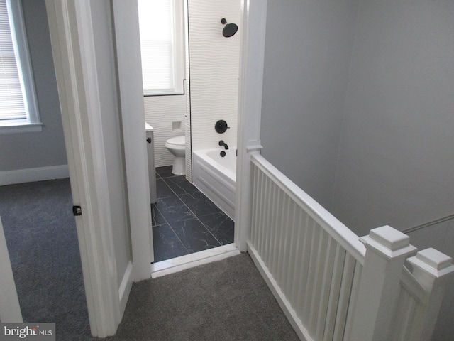 bathroom with a healthy amount of sunlight, a tub, and toilet