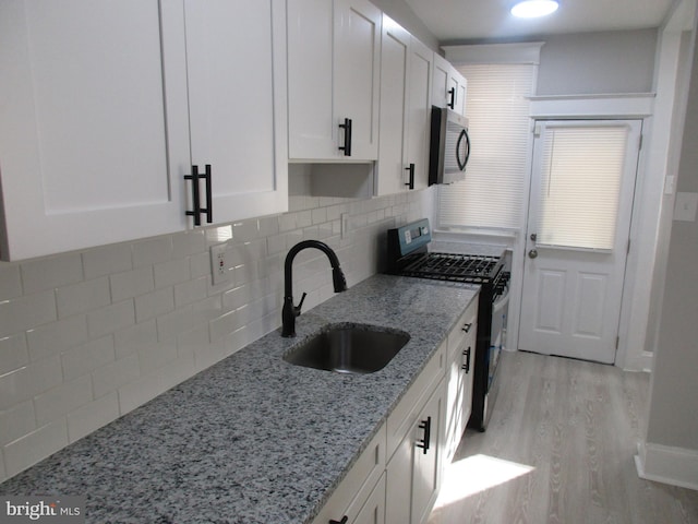 kitchen featuring sink, light hardwood / wood-style flooring, white cabinetry, appliances with stainless steel finishes, and light stone countertops