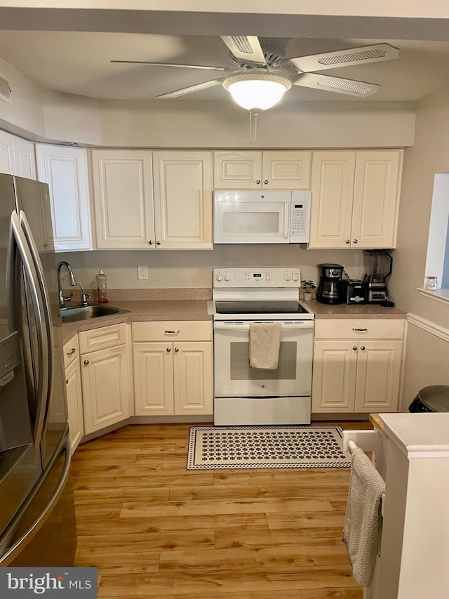 kitchen with white appliances, sink, light wood-type flooring, white cabinetry, and ceiling fan