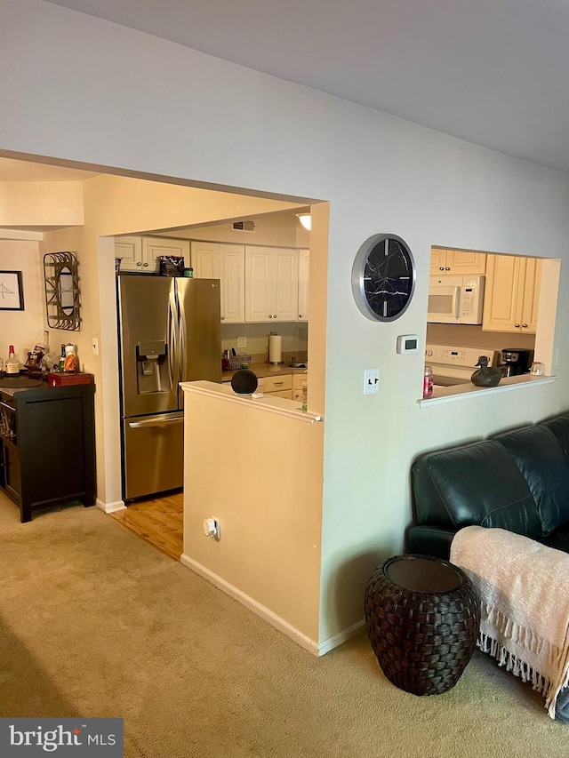 kitchen featuring stove, light colored carpet, and stainless steel fridge with ice dispenser