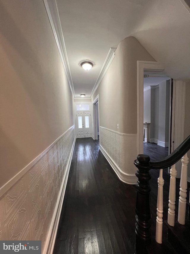 corridor with stairs, dark wood-type flooring, ornamental molding, and a wainscoted wall