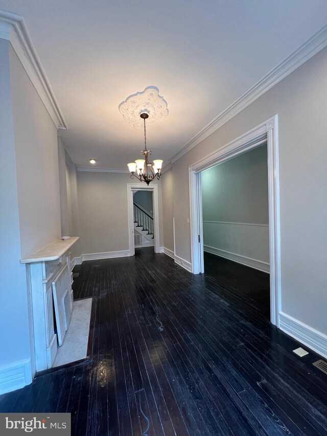 unfurnished living room with dark hardwood / wood-style floors, a chandelier, and crown molding