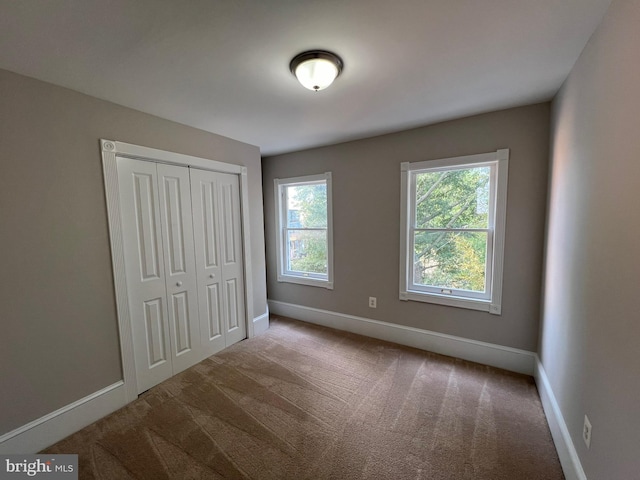 unfurnished bedroom featuring light carpet and a closet