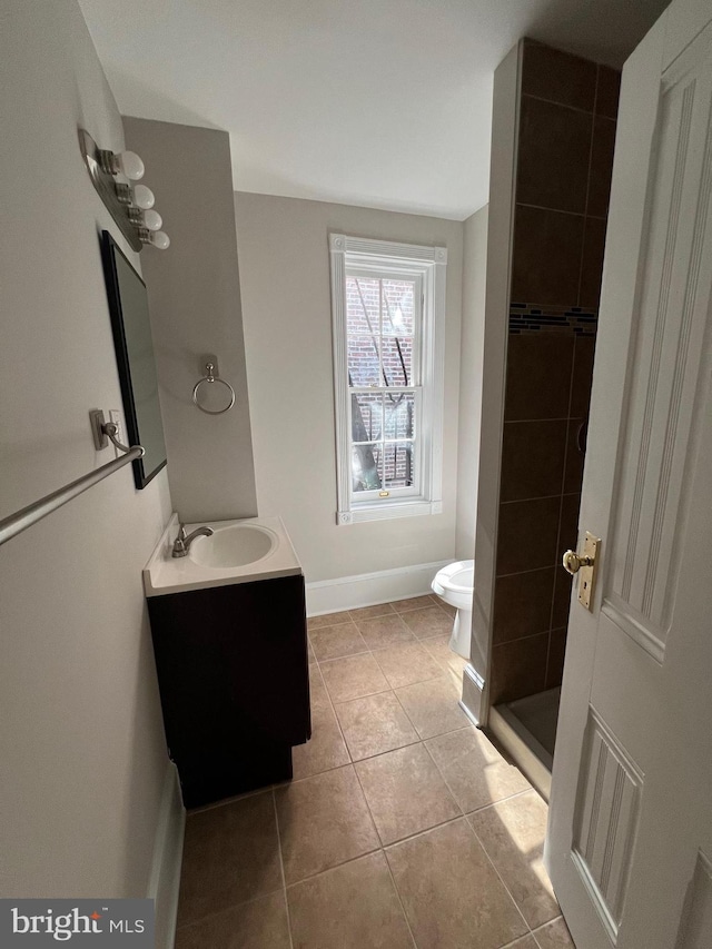 bathroom with a tile shower, tile patterned flooring, vanity, and toilet