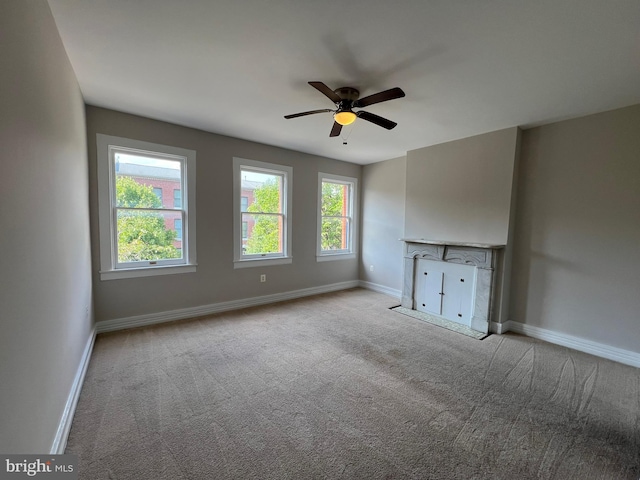 unfurnished living room with baseboards, carpet flooring, and ceiling fan