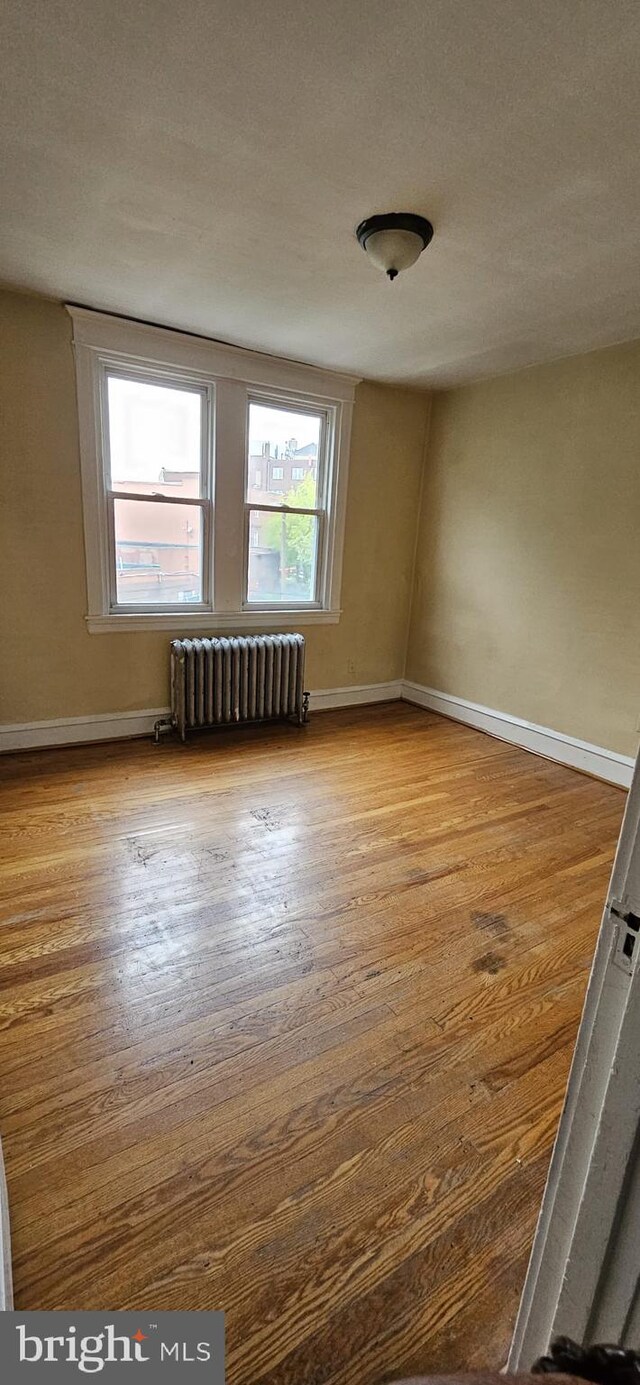 spare room with radiator heating unit and light hardwood / wood-style floors