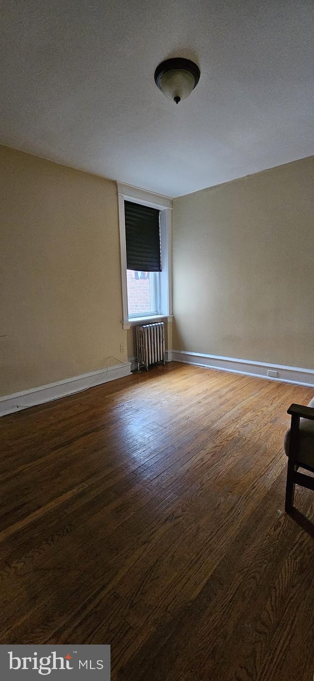 unfurnished room featuring dark wood-type flooring, a textured ceiling, and radiator