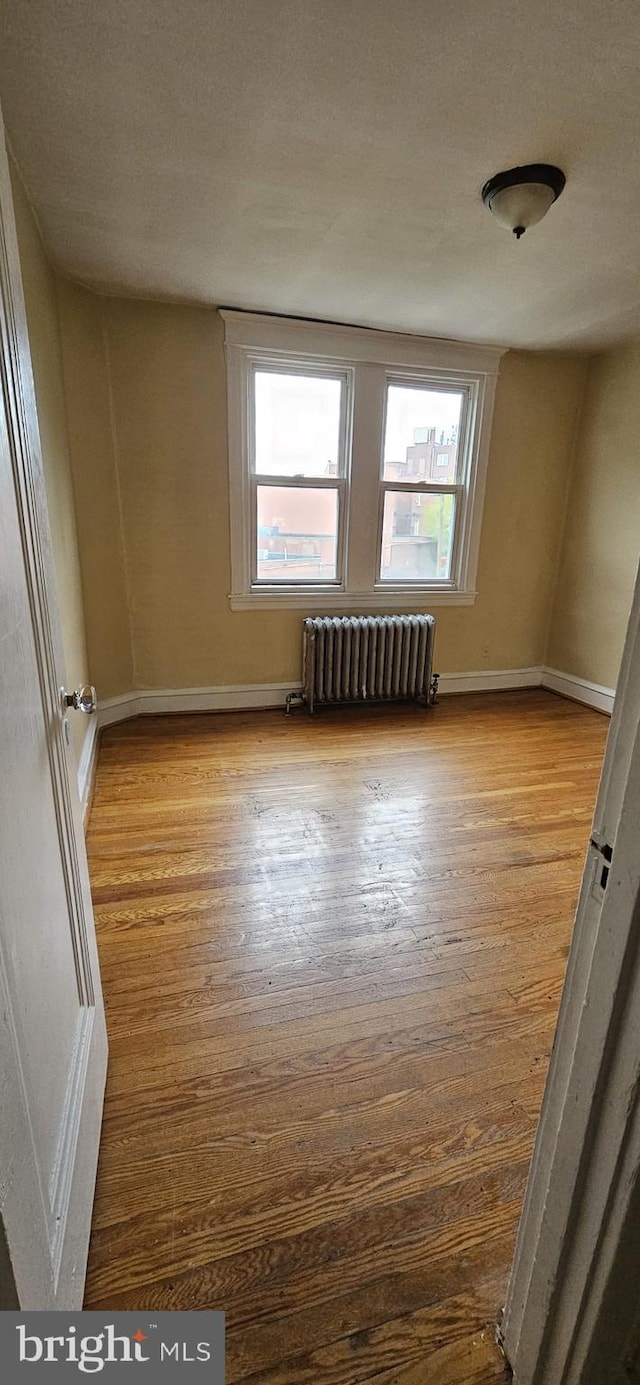 spare room with light wood-type flooring and radiator heating unit