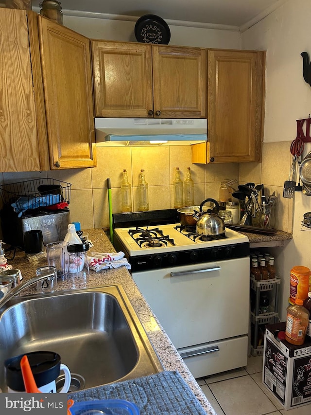 kitchen featuring sink, light tile patterned floors, tasteful backsplash, and white range oven