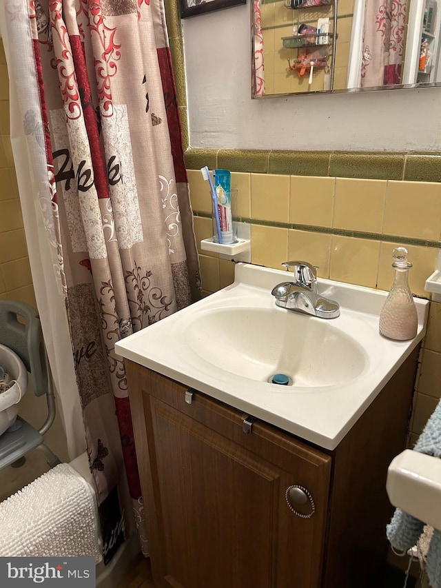 bathroom with tasteful backsplash, a shower with curtain, vanity, and tile walls