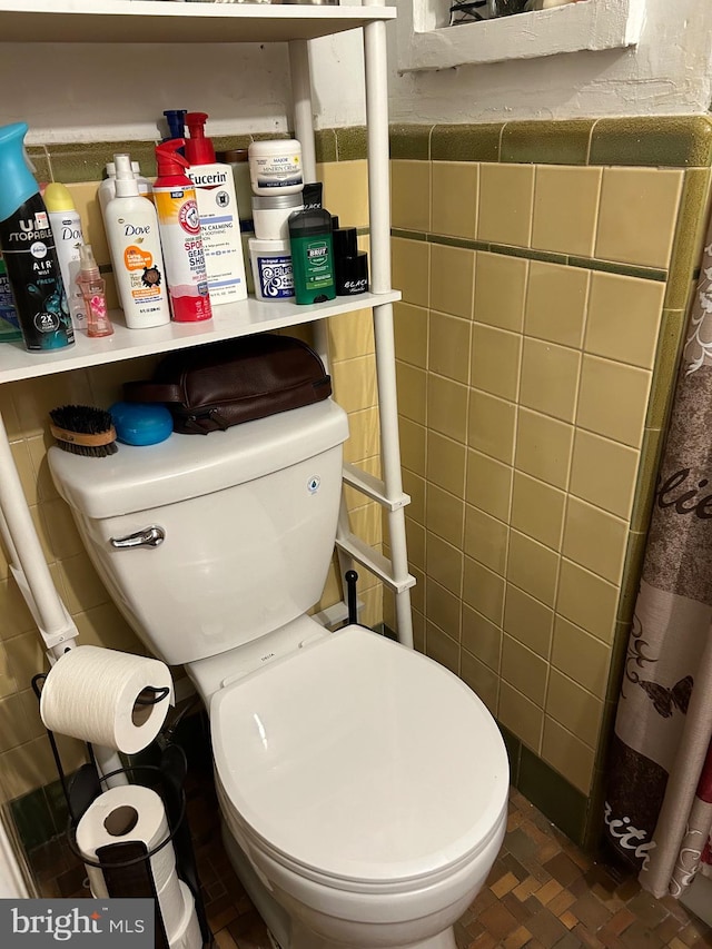 bathroom featuring tile walls, toilet, and curtained shower