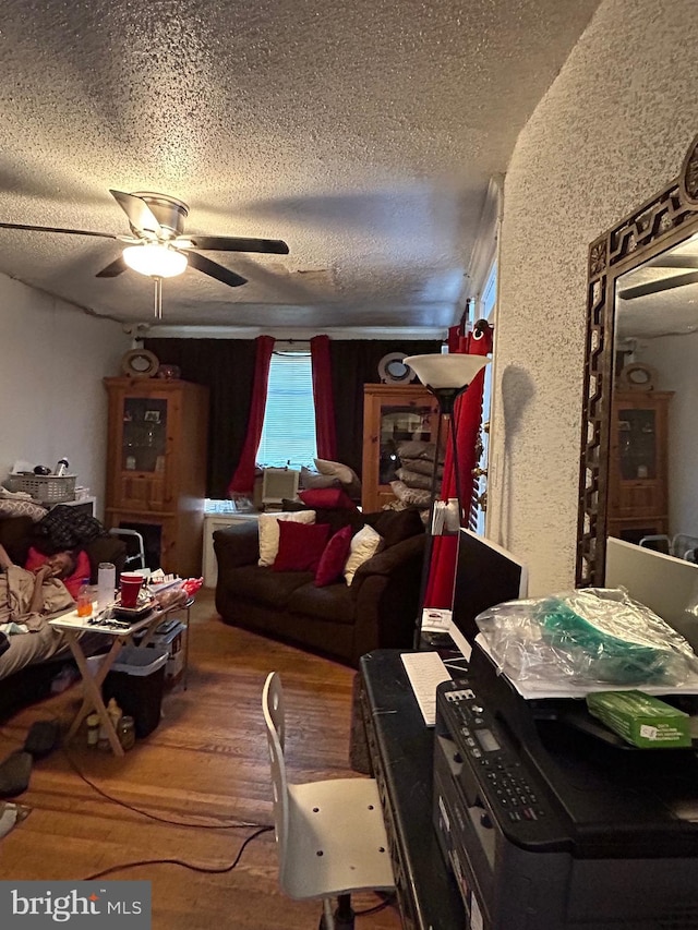 living room featuring ceiling fan, wood-type flooring, and a textured ceiling