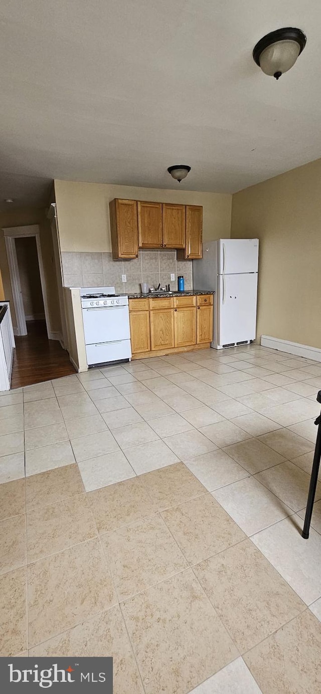 kitchen with white appliances, sink, light tile patterned floors, and tasteful backsplash