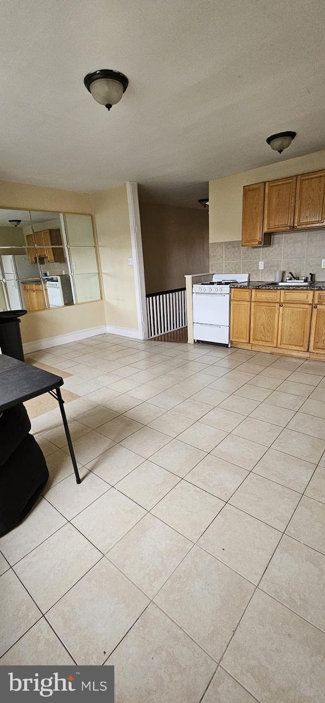 kitchen with backsplash, white range oven, and light tile patterned floors