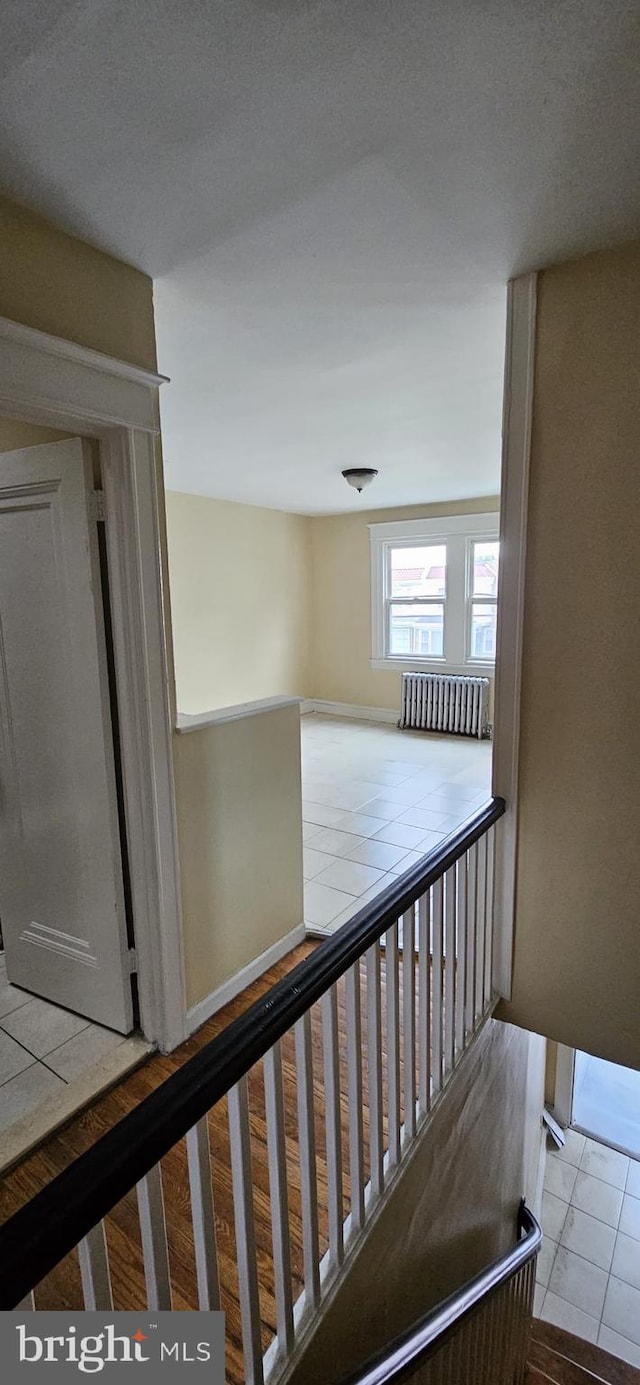 staircase with hardwood / wood-style floors and radiator heating unit