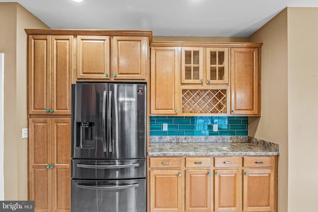 kitchen featuring stainless steel fridge and tasteful backsplash