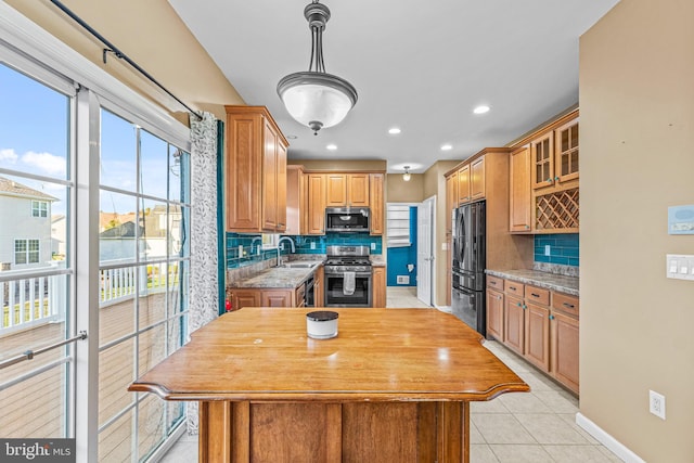 kitchen with sink, a kitchen island, stainless steel appliances, light stone counters, and decorative backsplash