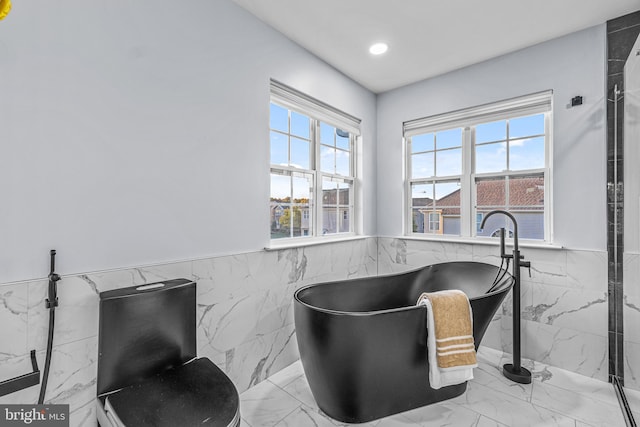 bathroom featuring a tub to relax in and tile walls