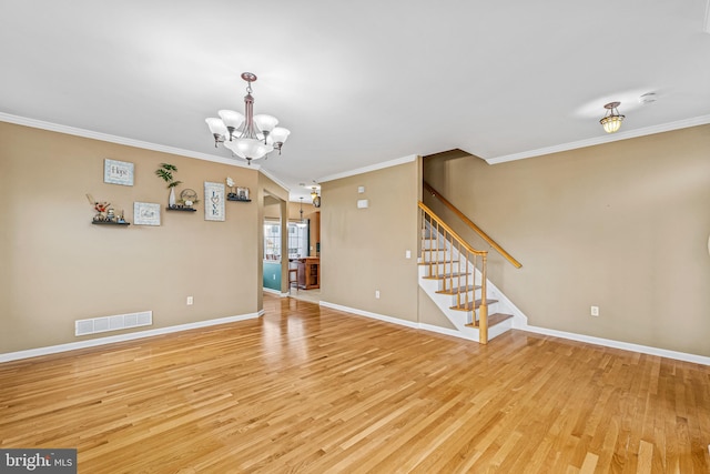 interior space with an inviting chandelier, ornamental molding, and light hardwood / wood-style floors