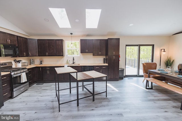 kitchen with light wood-type flooring, lofted ceiling with skylight, decorative light fixtures, sink, and black appliances