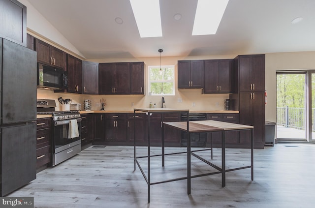 kitchen with black appliances, sink, light hardwood / wood-style floors, decorative light fixtures, and vaulted ceiling with skylight