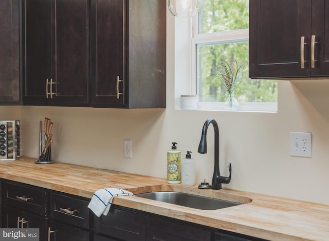 kitchen featuring dark brown cabinets, wood counters, and sink