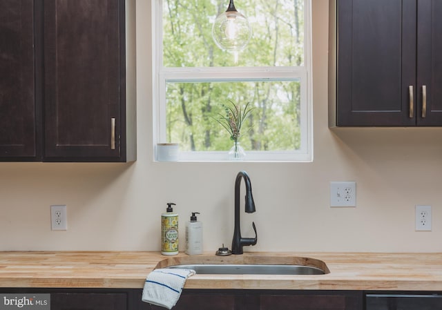 kitchen with dark brown cabinets, wood counters, and sink