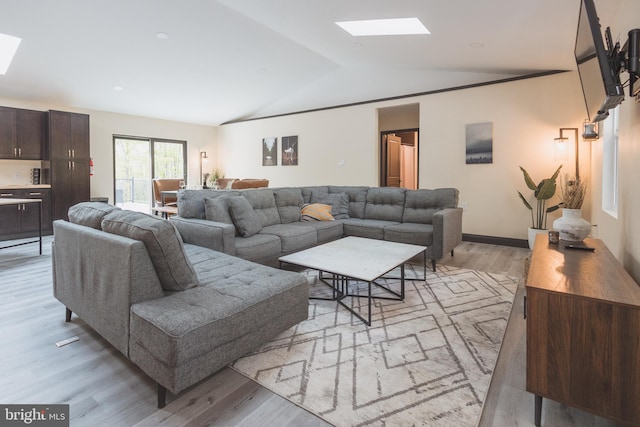 living room with light hardwood / wood-style floors and lofted ceiling with skylight