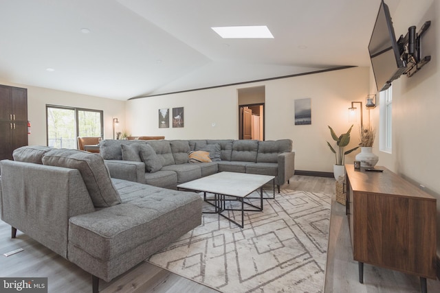 living room featuring light wood-type flooring and lofted ceiling with skylight