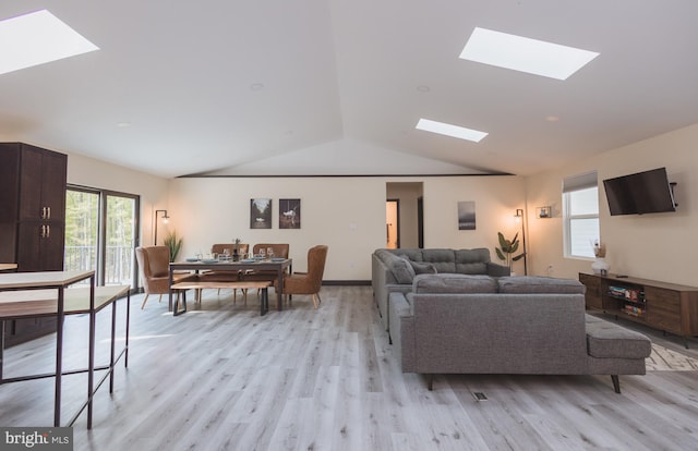 living room with lofted ceiling with skylight and light hardwood / wood-style flooring