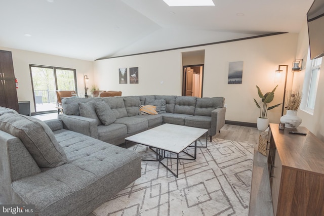 living room featuring vaulted ceiling with skylight and light wood-type flooring