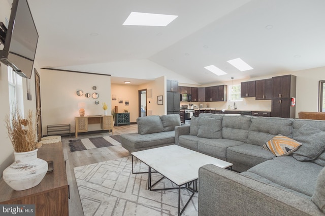 living room featuring sink, light wood-type flooring, and vaulted ceiling