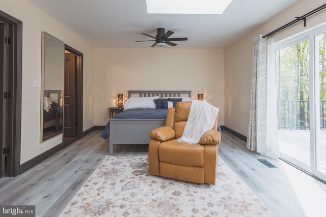 bedroom with ceiling fan, a skylight, light wood-type flooring, and access to exterior