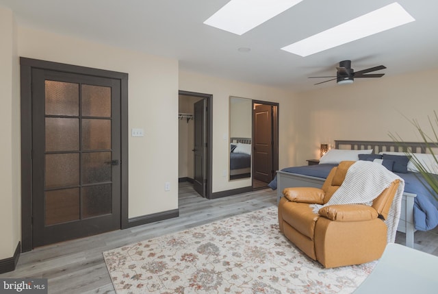 bedroom featuring a walk in closet, ceiling fan, a closet, and light hardwood / wood-style flooring