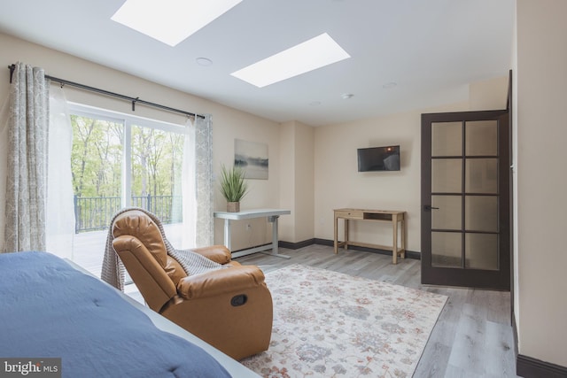 living room with a skylight, light wood-type flooring, and a baseboard radiator