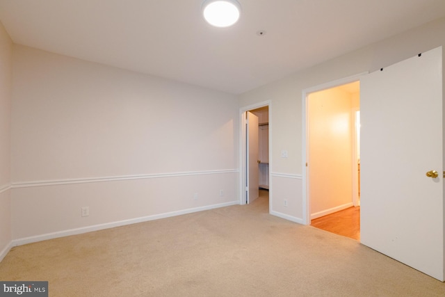 unfurnished bedroom featuring a walk in closet and light colored carpet