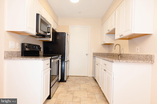 kitchen with light stone countertops, appliances with stainless steel finishes, sink, and white cabinetry