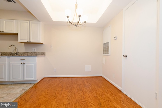 kitchen featuring an inviting chandelier, pendant lighting, light hardwood / wood-style flooring, sink, and white cabinetry