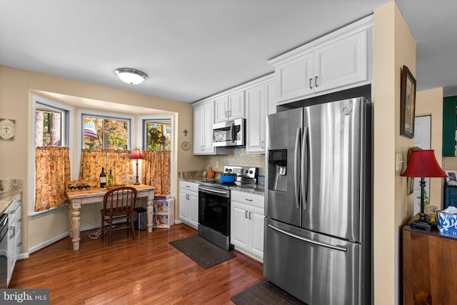 kitchen with appliances with stainless steel finishes, tasteful backsplash, white cabinets, and dark hardwood / wood-style flooring