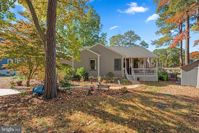 view of front of property featuring an outdoor structure, covered porch, a storage unit, a sunroom, and a front lawn