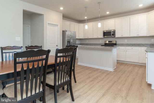 kitchen with stainless steel appliances, white cabinets, and light hardwood / wood-style flooring