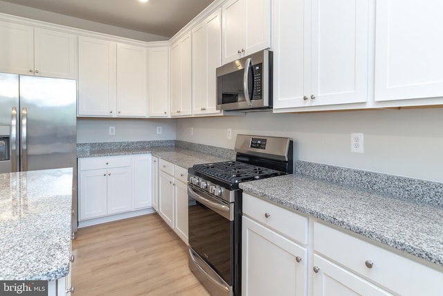 kitchen featuring stainless steel appliances, light stone countertops, light hardwood / wood-style floors, and white cabinetry