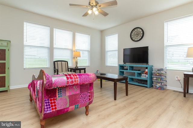 living room with ceiling fan, light wood-type flooring, and a healthy amount of sunlight