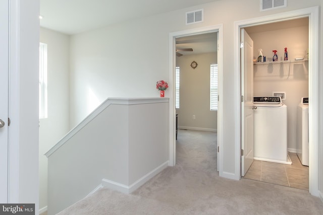 corridor featuring light carpet and washer and dryer