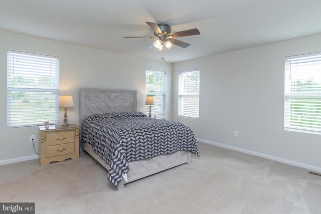 carpeted bedroom featuring multiple windows and ceiling fan