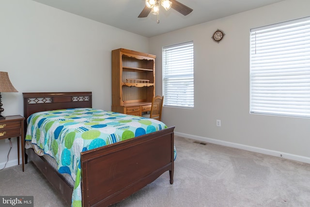 bedroom with multiple windows, ceiling fan, and light colored carpet