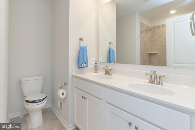 bathroom with tile patterned floors, vanity, tiled shower, and toilet